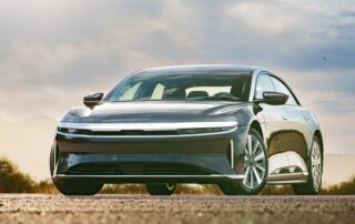 A dark grey Lucid Air luxury electric car parked outdoors at sunset.