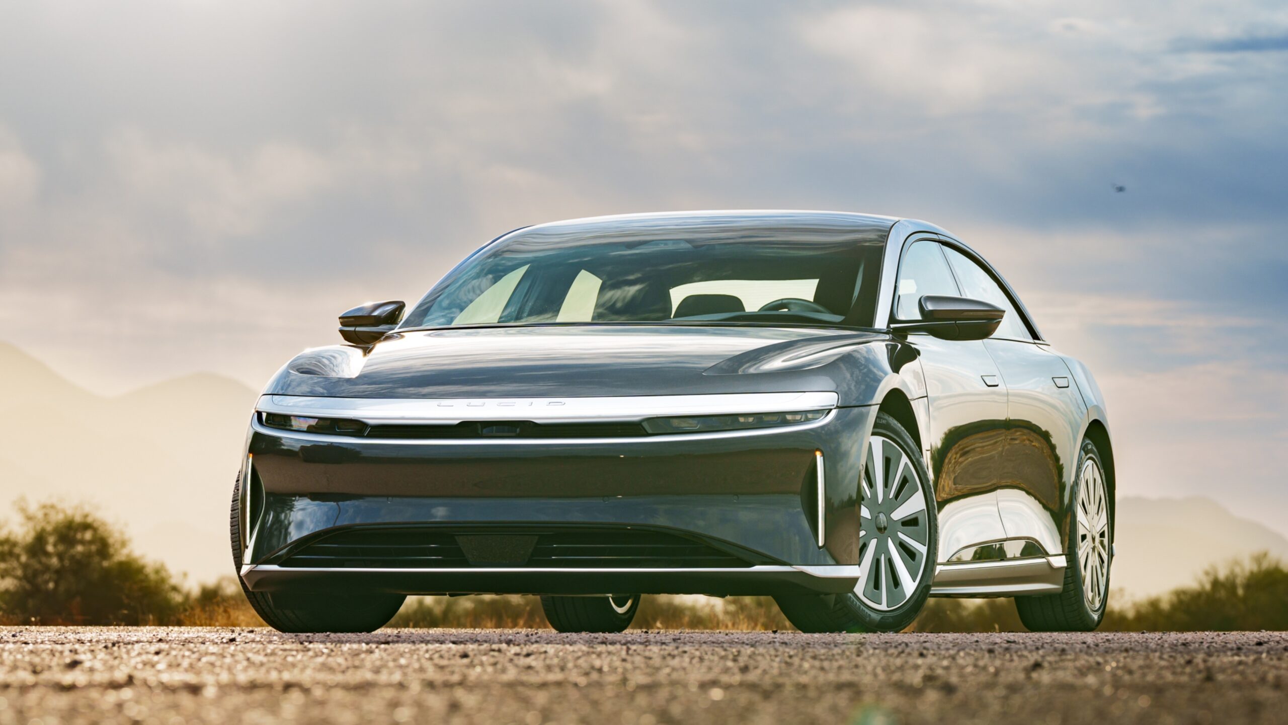 A dark grey Lucid Air luxury electric car parked outdoors at sunset.