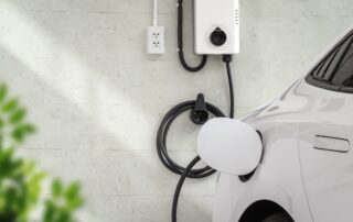 Wall-mounted Level 2 EV charger station installed on a garage wall charging a white electric vehicle.